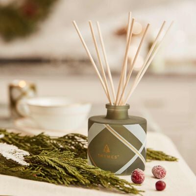 Thymes Frasier Fir Frosted Plaid Petite Reed Diffuser in use on table